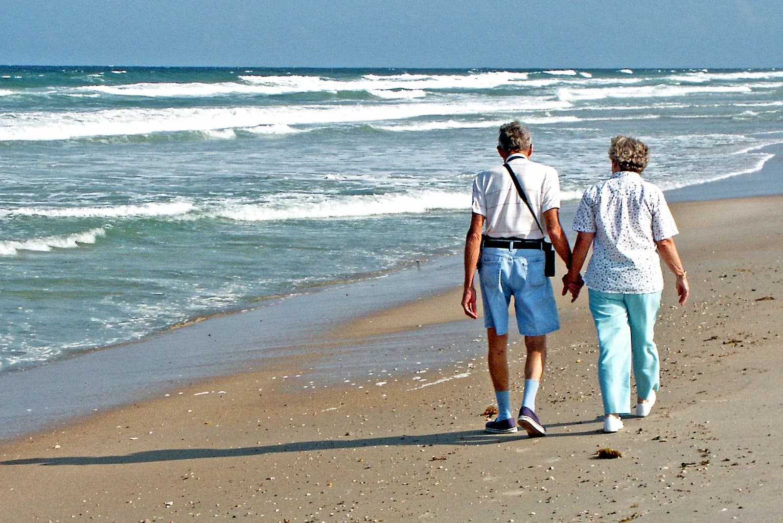 Pareja mayor caminando por la playa con visión clara